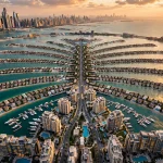 Aerial view of luxury villas and residences on Palm Jumeirah, Dubai at golden hour, with the Marina skyline in the distance