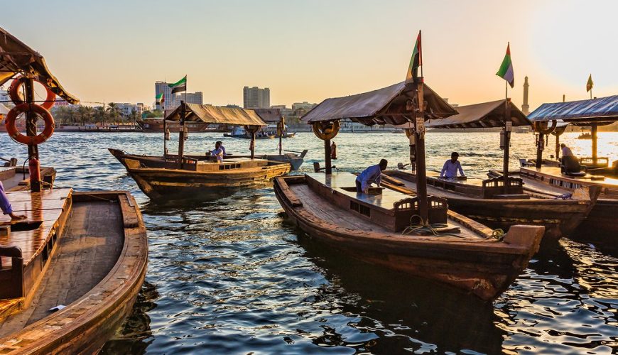 Traditional abra boats crossing Dubai Creek at sunset
