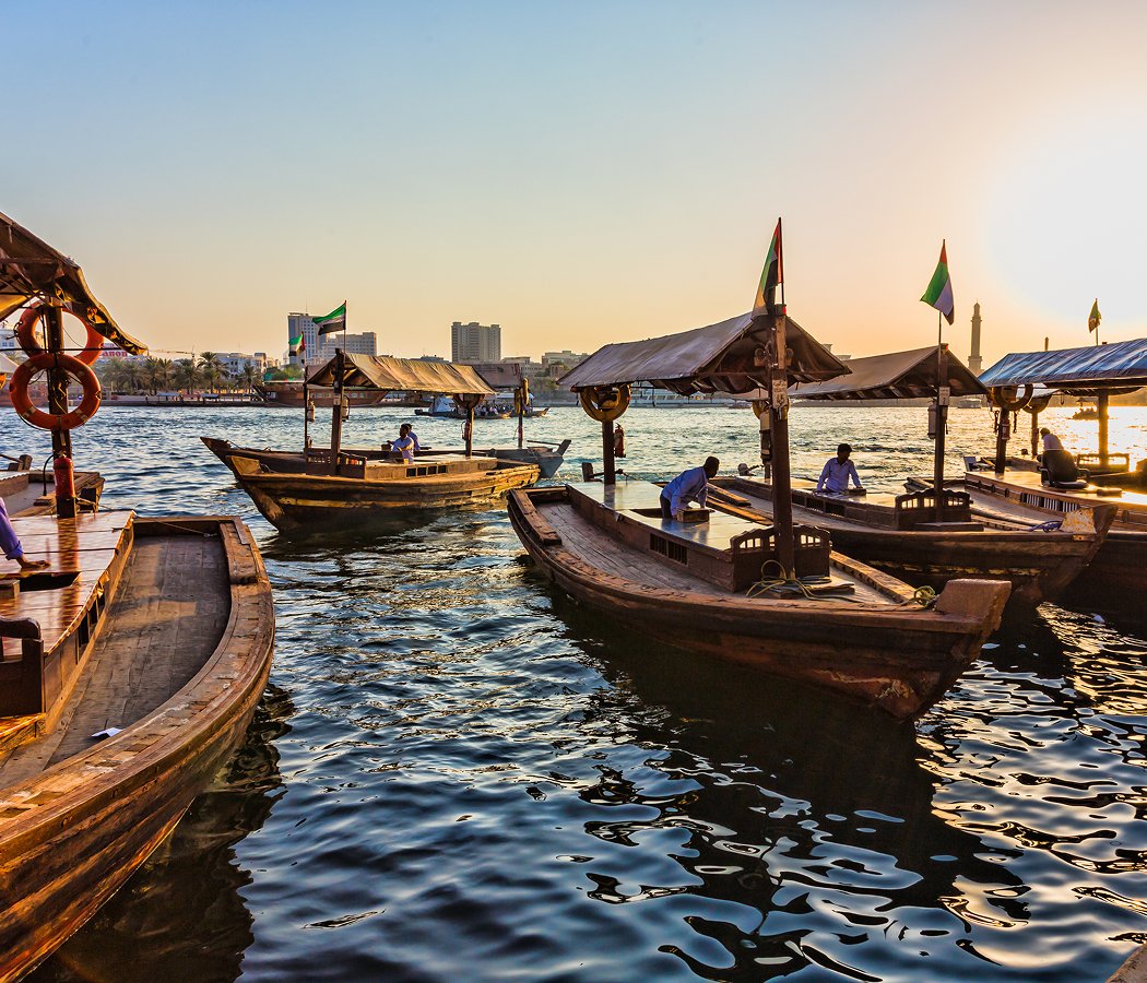Traditional abra boats crossing Dubai Creek at sunset