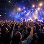 Concert crowd at a Dubai arena show with stage lights and raised hands
