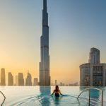 Infinity pool at a Dubai hotel with the Burj Khalifa rising behind it at sunset