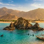 Snoopy Island rock formation off the Fujairah coast with turquoise water and the Hajar Mountains behind