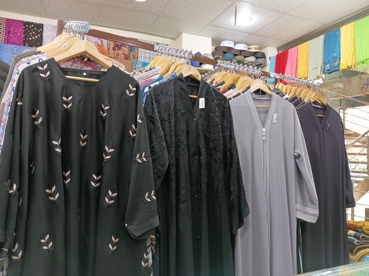 Abayas and colorful fabrics on display inside a traditional market shop in Deira
