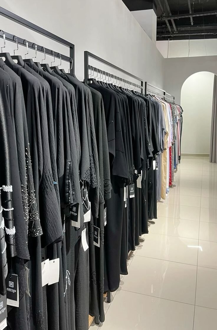 Rows of black abayas hanging on racks inside a modern Dubai boutique