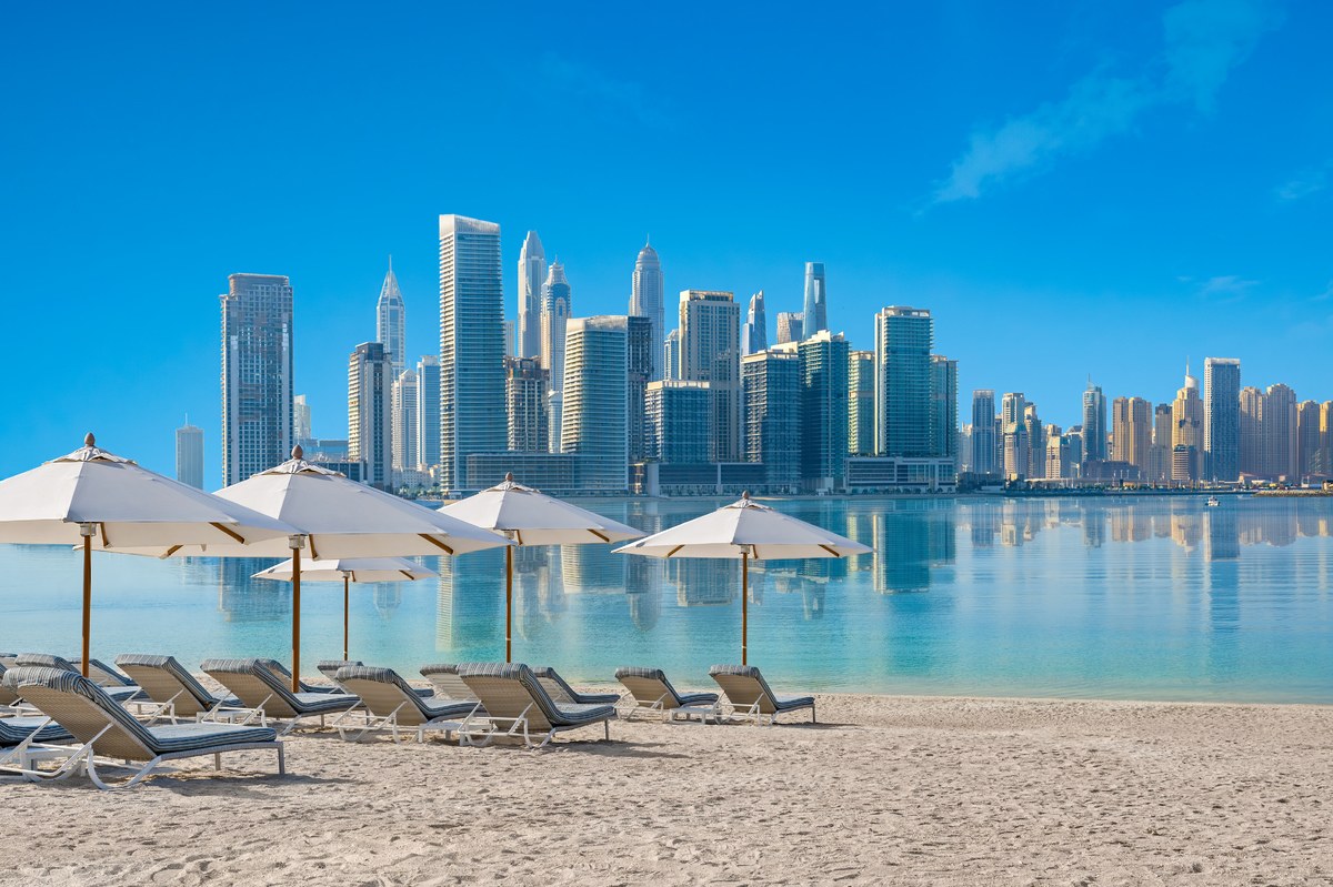 Sun loungers and umbrellas on a Dubai beach with the Marina skyline beyond
