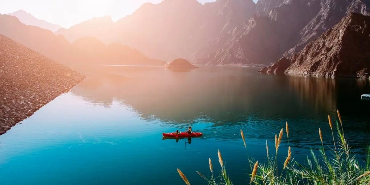 Kayaks floating on Hatta Dam with mountains rising behind the turquoise water