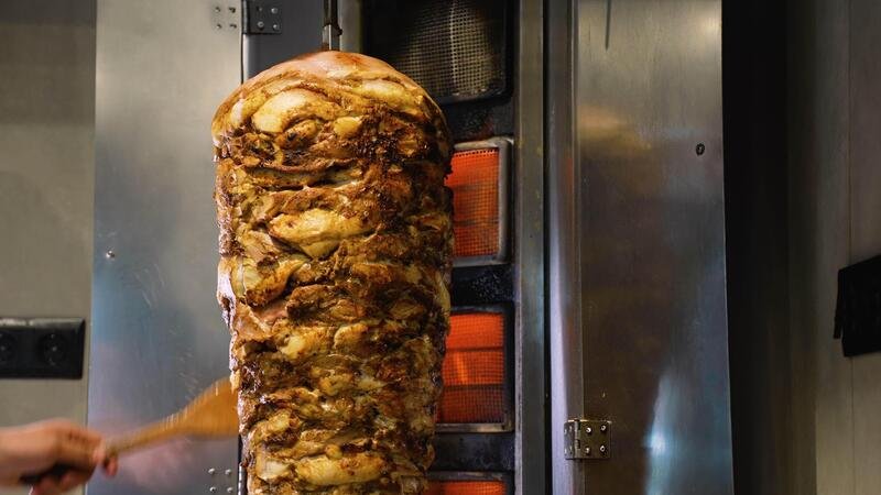 Shawarma meat grilling on a vertical spit at a Dubai cafeteria