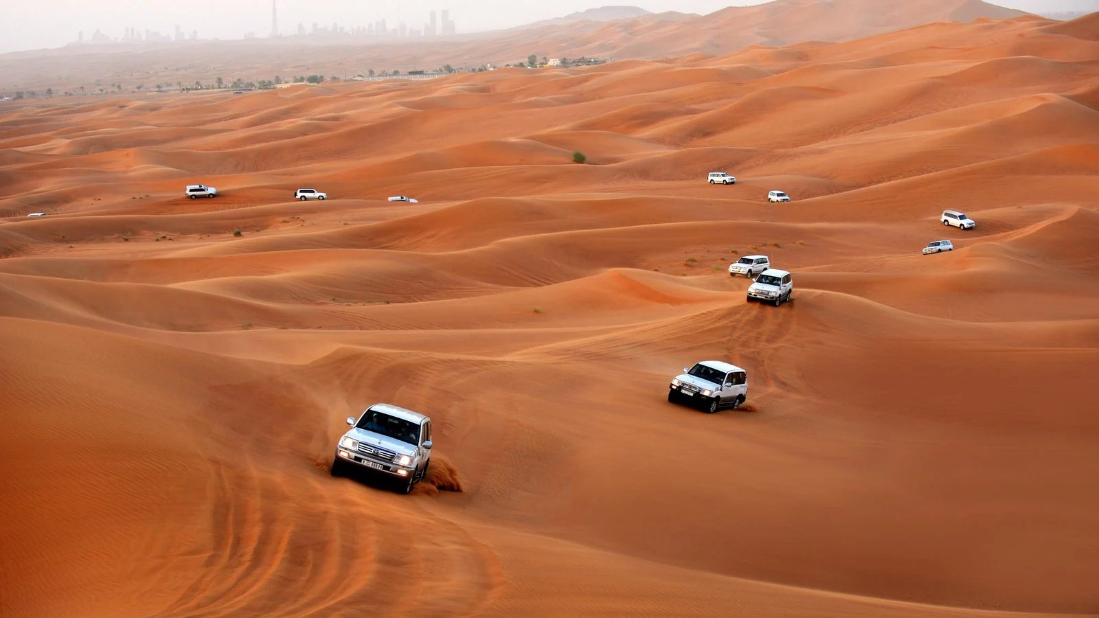 4x4 jeeps dune bashing across red desert dunes near Dubai