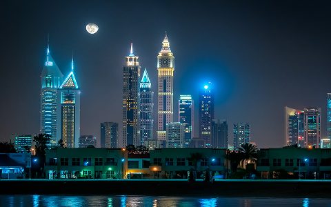 Dubai skyline glowing at night as seen from Jumeirah Beach