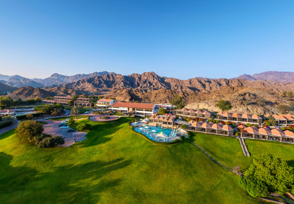 JA Hatta Fort Hotel low buildings and pool in gardens below Hajar mountains
