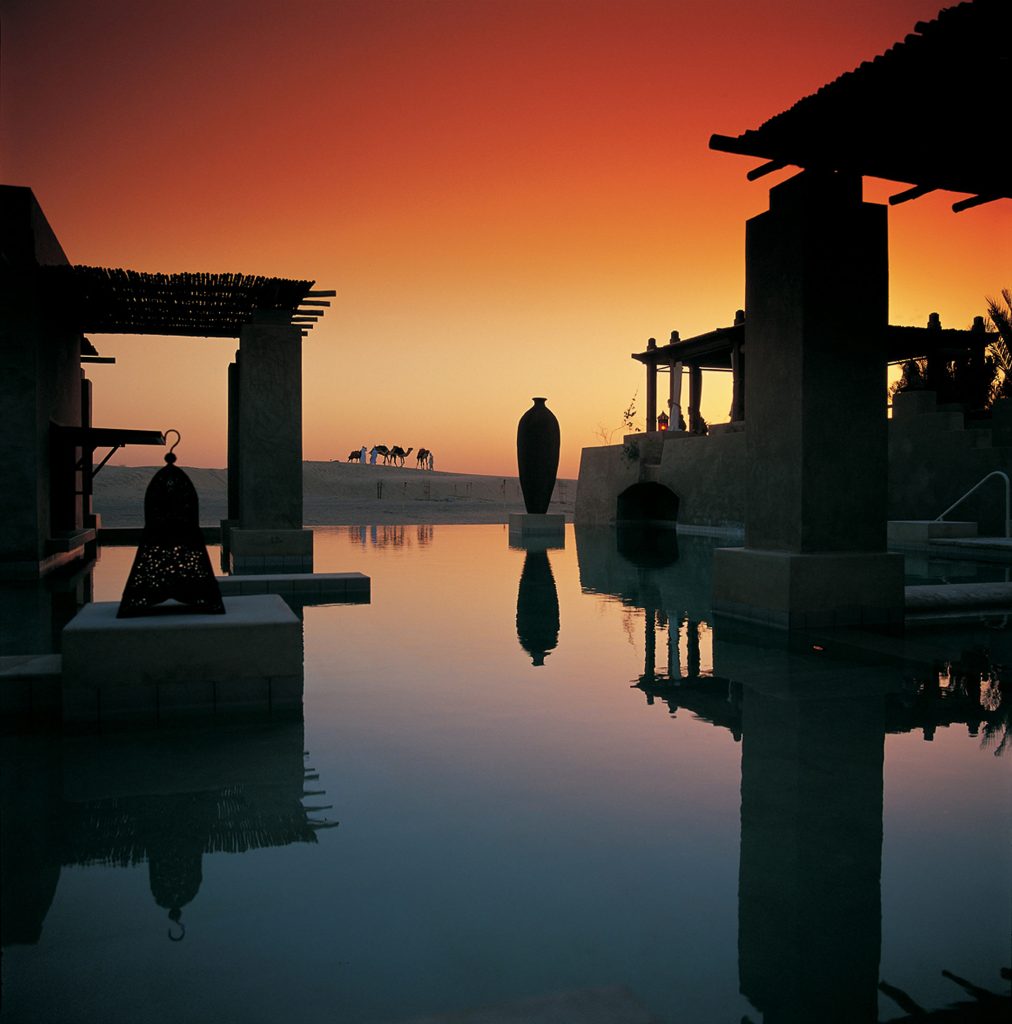 Bab Al Shams desert resort pool and low Arabian-style buildings at sunset