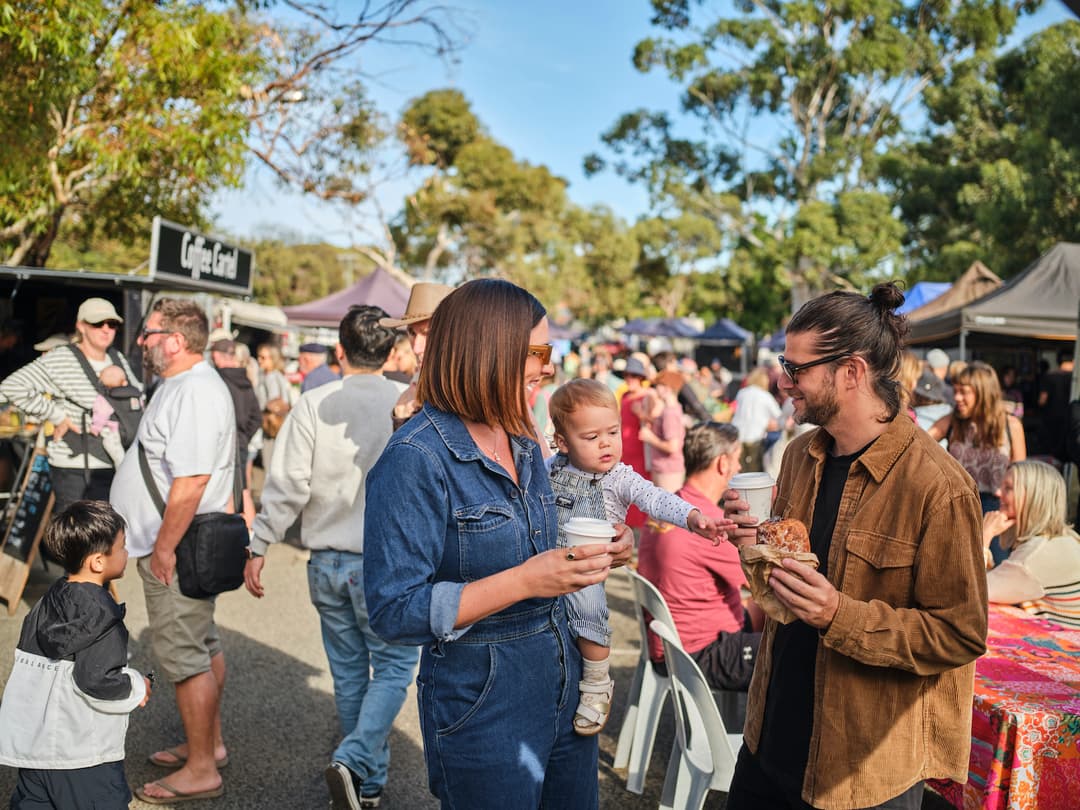 Families at an outdoor weekend market with food stalls