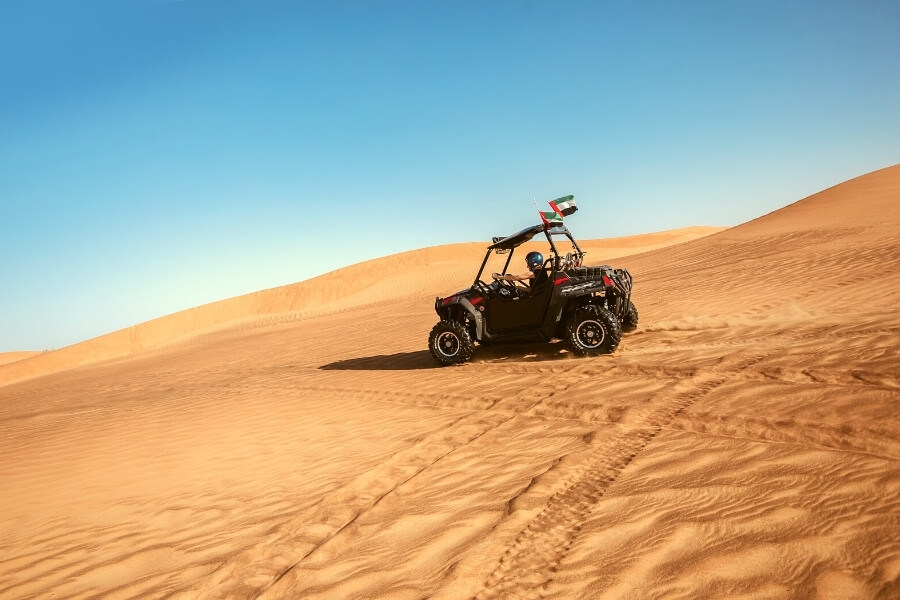 Dune buggy driving across red desert dunes in Dubai