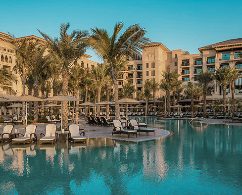 Low-rise resort buildings and palm trees beside a quiet pool near Jumeirah Beach
