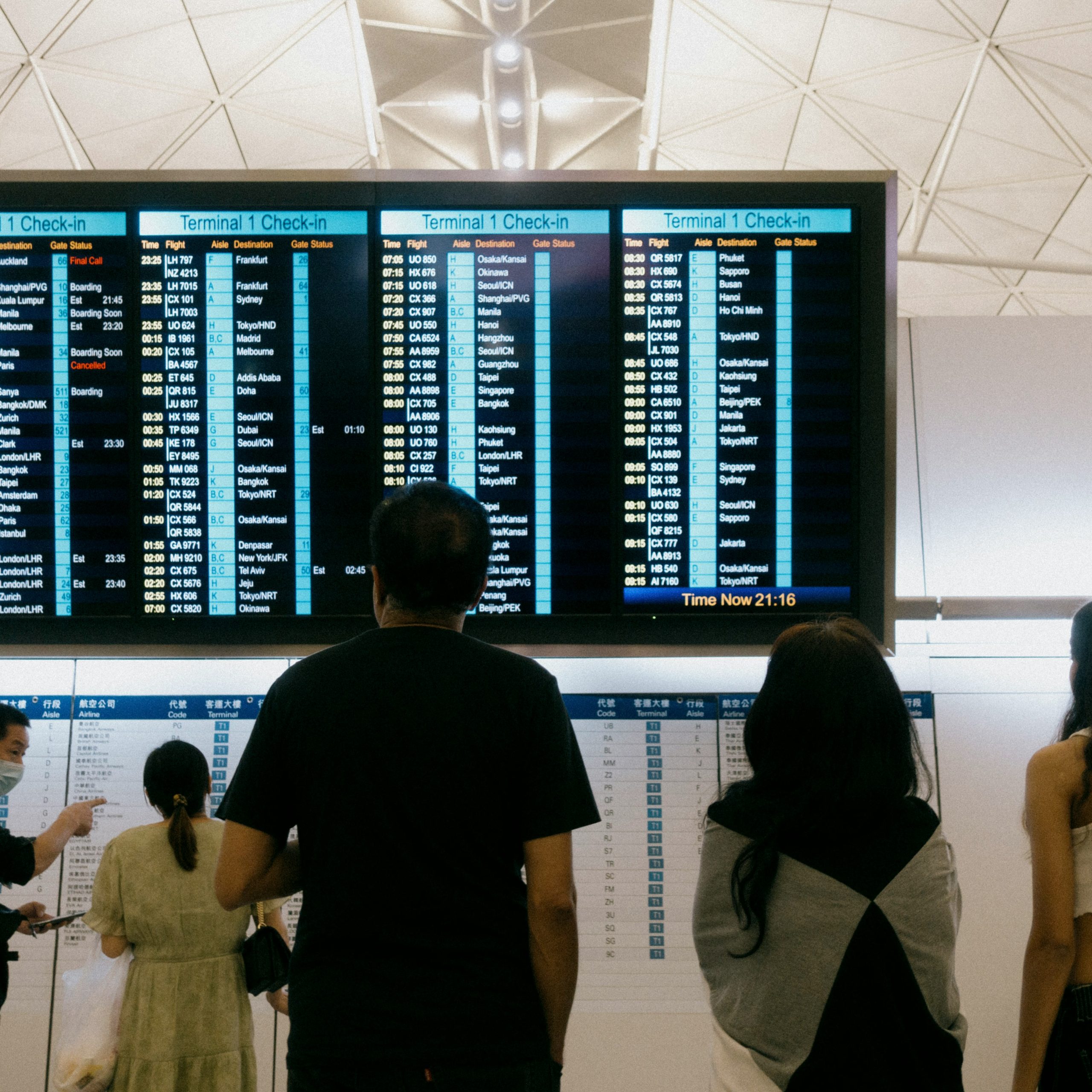 Passengers checking a departure board in an airport terminal