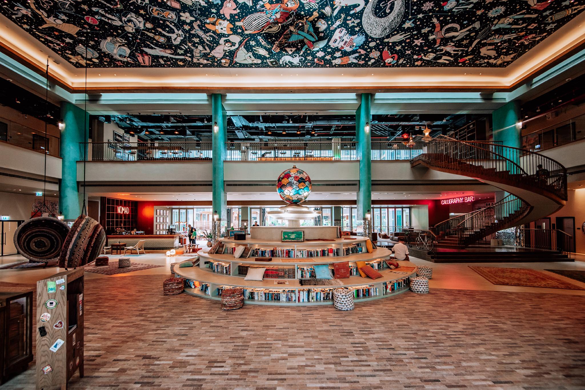 25hours Hotel One Central eclectic lobby with solo guests at cafe tables