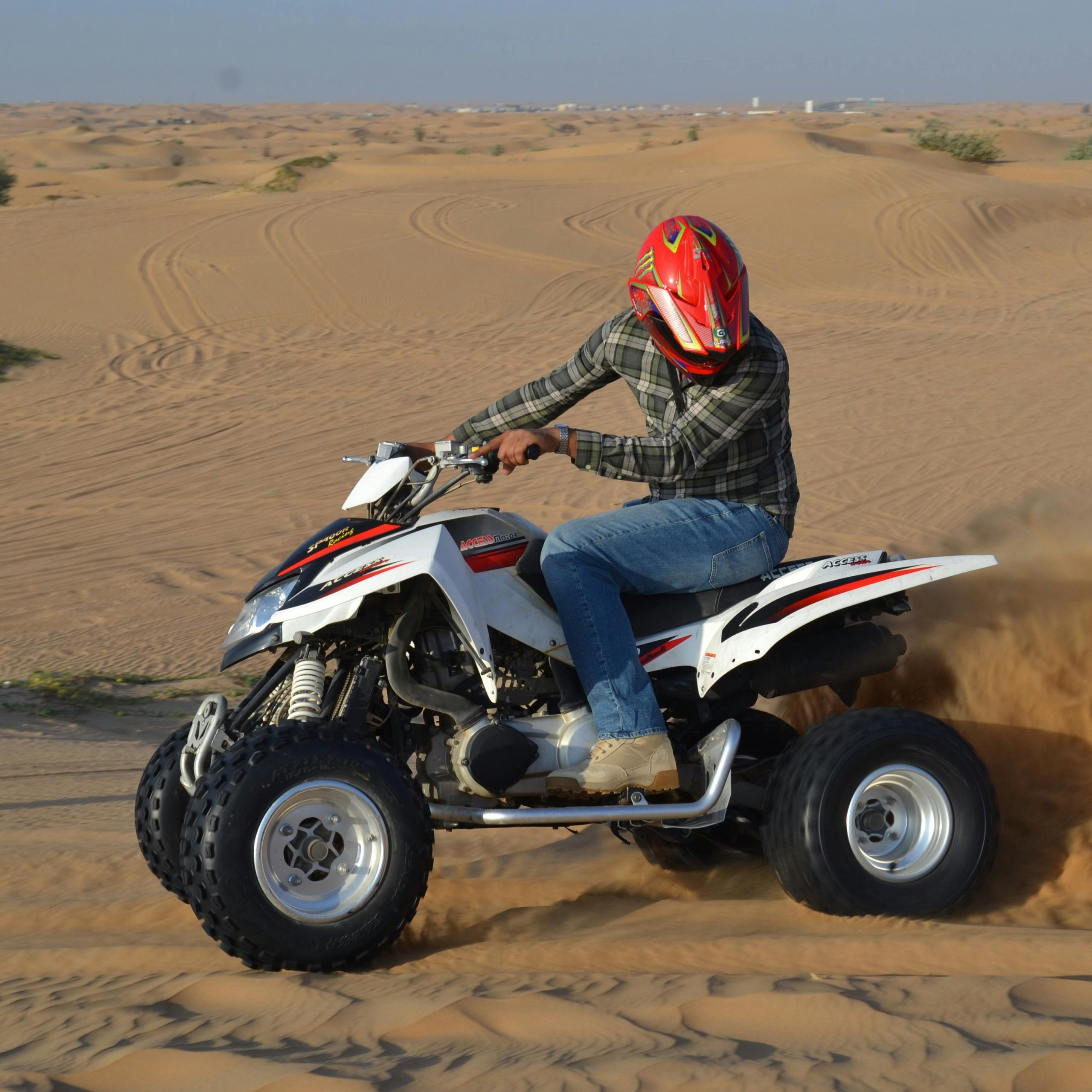 Tourist riding a quad bike across sandy desert tracks in Dubai