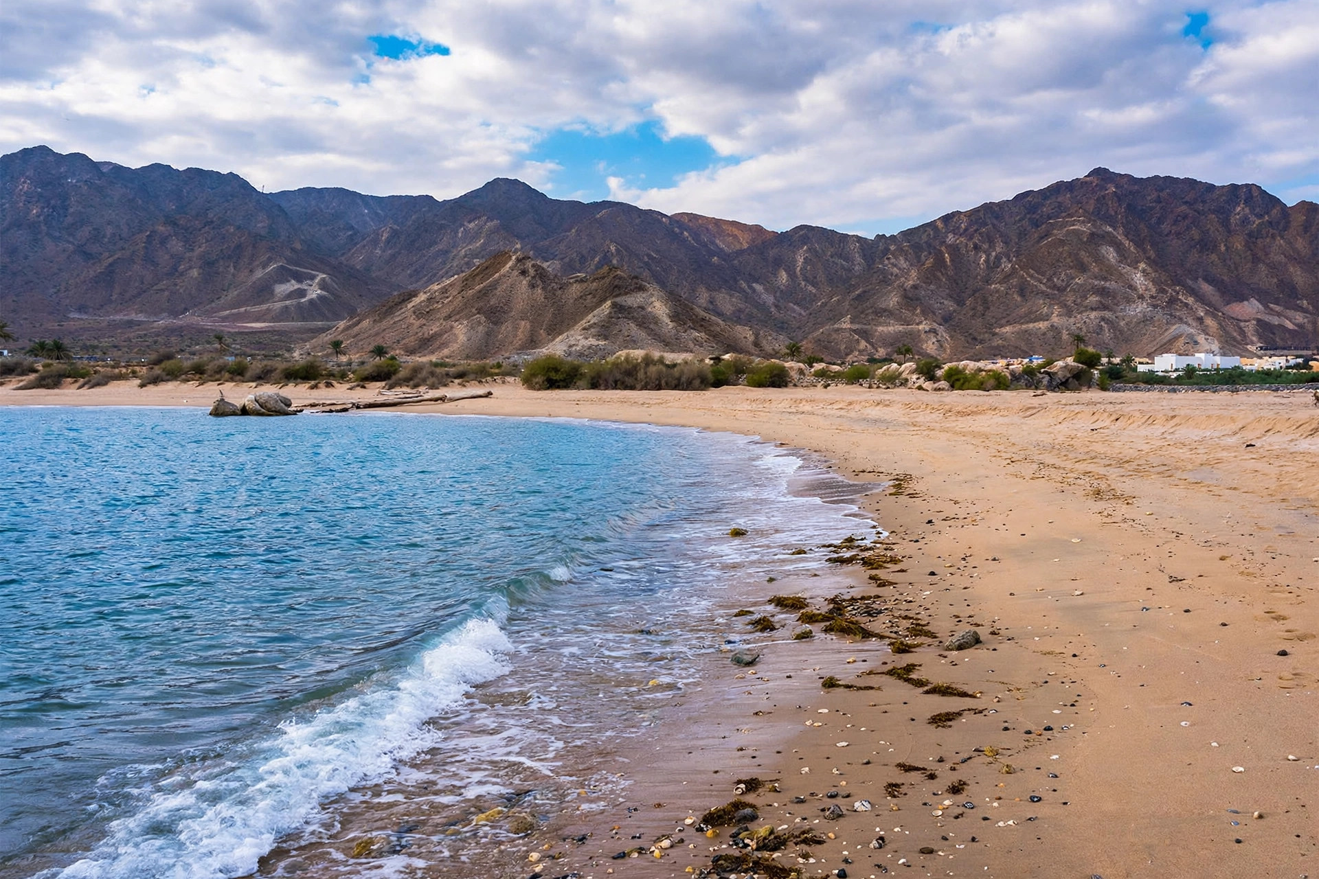 Partly cloudy sky over a Fujairah beach and mountains