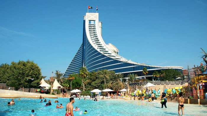 Wave-shaped hotel beside palm trees and family pools facing the sea
