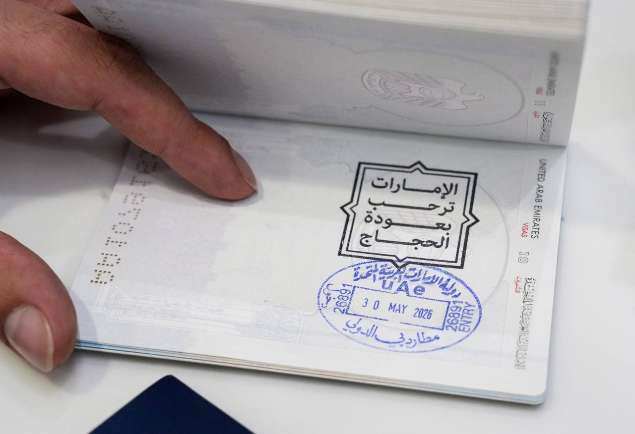 A passport open at a UAE entry visa page with stamps