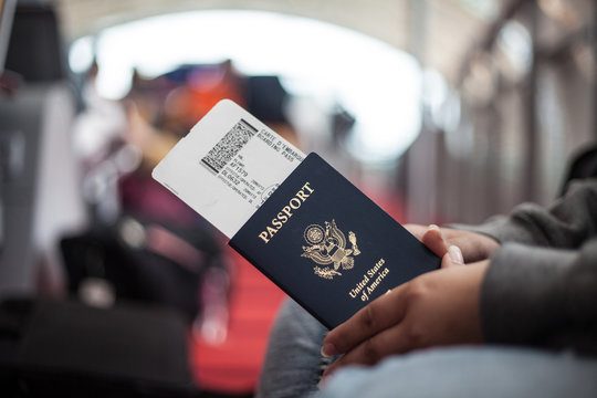 A traveller holding a passport and boarding pass at an airport