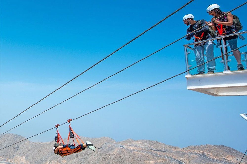 Rider in superman position launching on the Jais Flight zipline high above the Hajar mountains