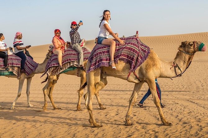 Tourists riding camels in a caravan across the Dubai desert on a desert safari