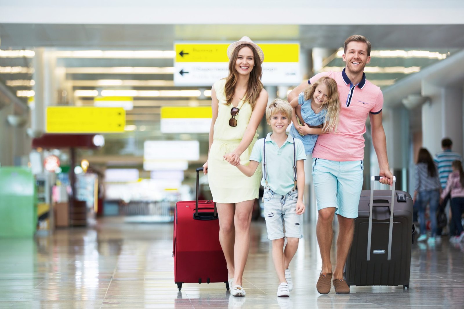 A family travelling through an airport with luggage