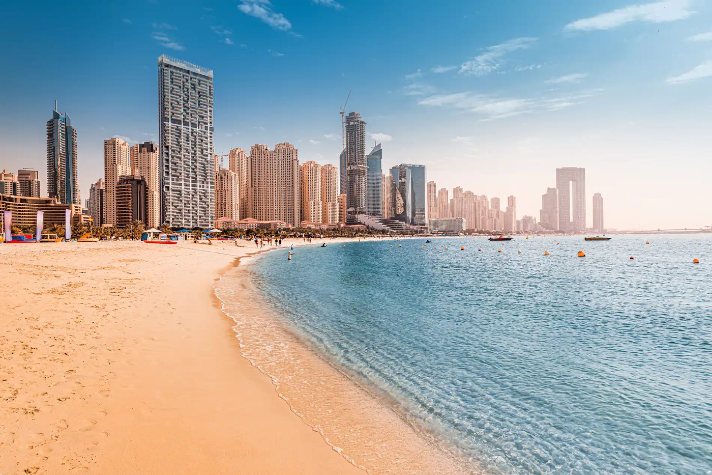 Dubai Marina towers and JBR beach with people walking the promenade