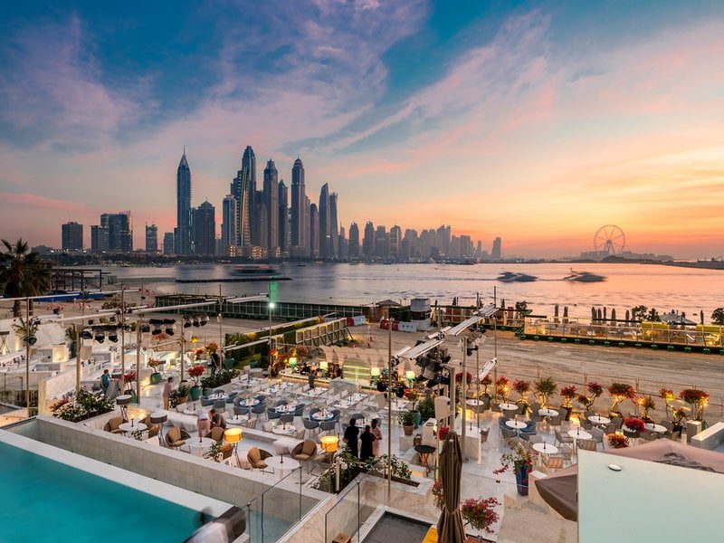 A beach club on Palm Jumeirah at sunset with the Dubai skyline behind