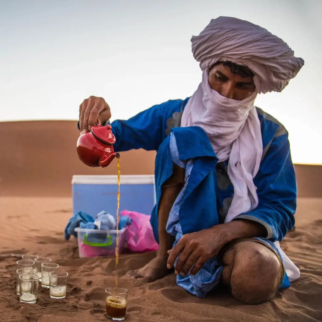 Traveller drinking water and resting in shade during a desert tour