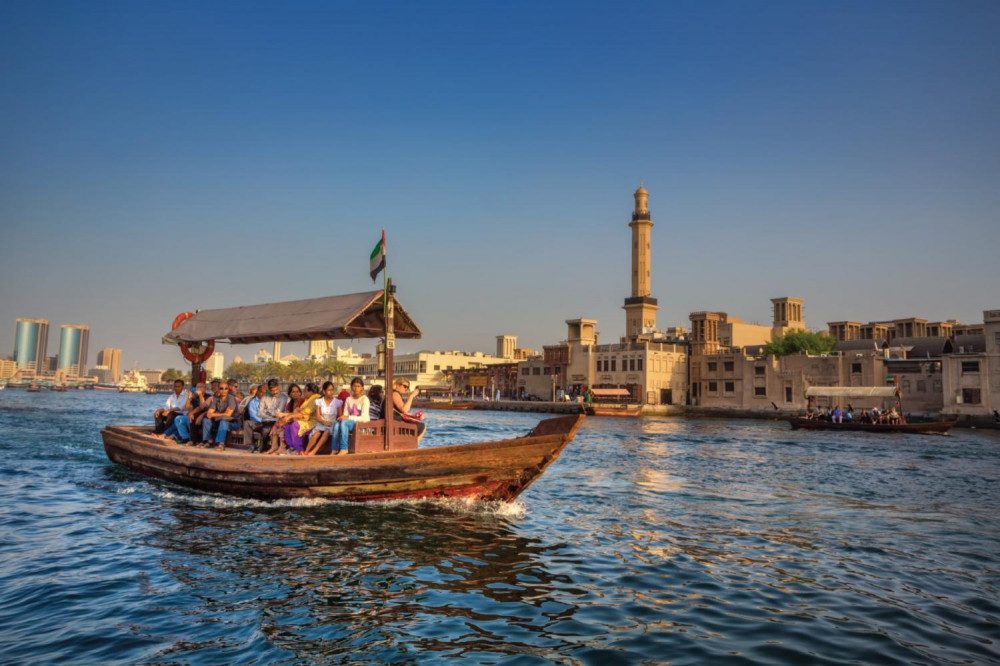 A family riding a traditional abra boat across Dubai Creek