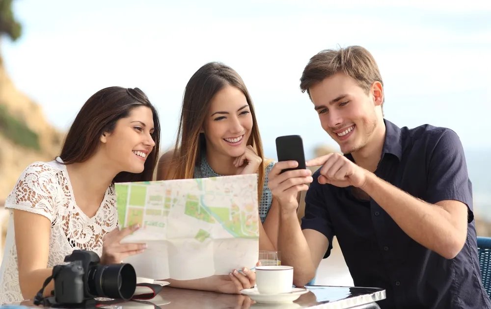 Friends comparing activity prices on a phone at a Dubai cafe