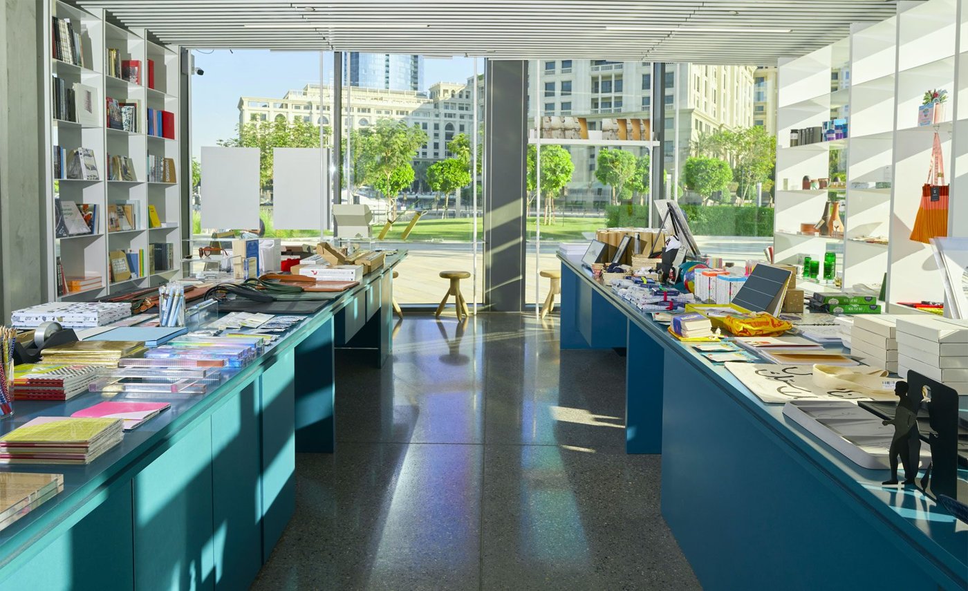 Tourists browsing books and prints in a small museum shop in Dubai
